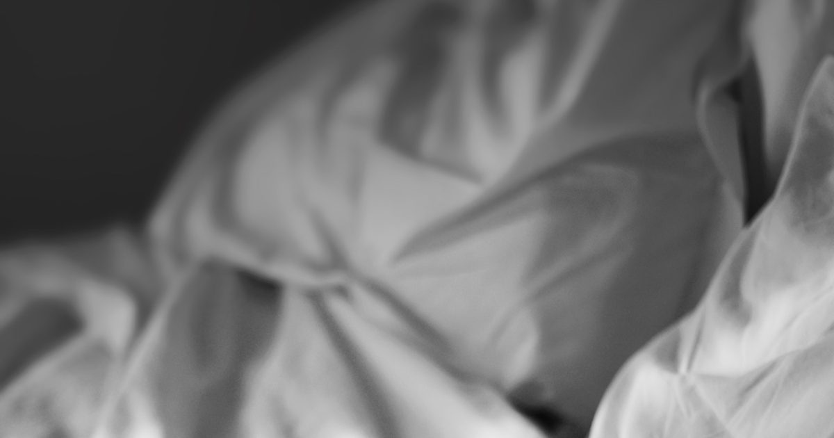 Soft rumpled white bedding and linens in gentle black and white light